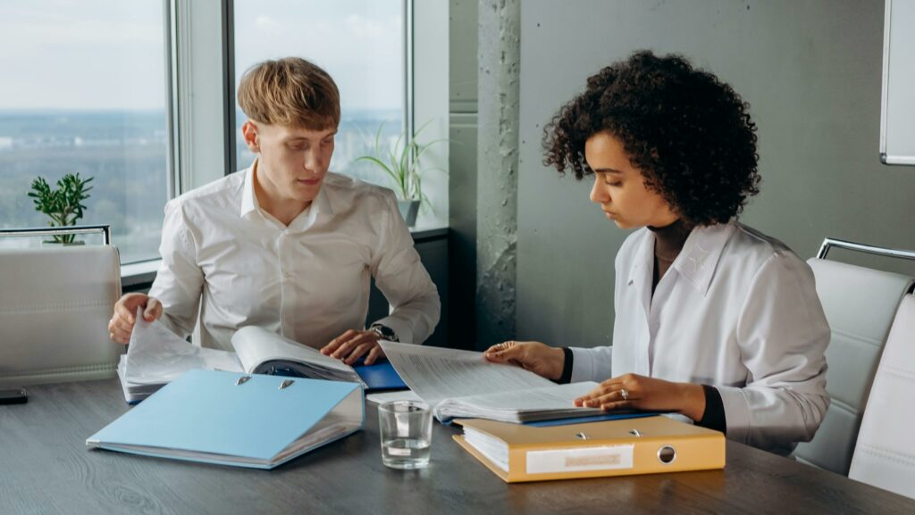 Two business colleagues analyzing financial reports at a desk in a modern office environment.